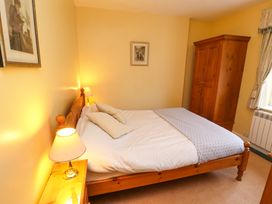 A bedroom with a wooden bed with pillows bedside tables with lamps a wardrobe and framed pictures on the walls at Maiden Moor in Grange near Keswick