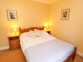 A bedroom with a wooden bed frame bedside tables with lamps and framed pictures on the walls at Maiden Moor in Grange near Keswick