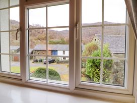 A view through a window showing stone buildings a car bushes and hills in the background at Maiden Moor in Grange near Keswick