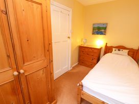A bedroom with a wooden bed and white bedding a wooden dresser with a lamp a wooden wardrobe and a white door at Maiden Moor in Grange near Keswick