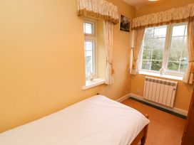A bedroom with a single bed near two windows with curtains and a radiator under one window at Maiden Moor in Grange near Keswick