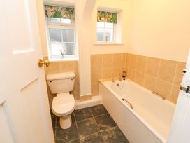 A bathroom with a toilet and a bathtub with tiled walls and two windows at Maiden Moor in Grange near Keswick