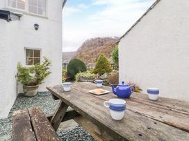 A wooden picnic table with a blue teapot cups and a plate of biscuits between white buildings with a mountain in the background at Maiden Moor in Grange near Keswick