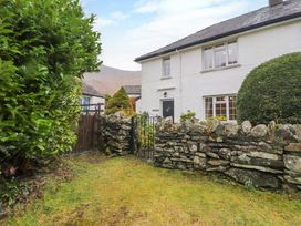 A garden with a stone wall and metal gate in front of a white two story house at Maiden Moor in Grange near Keswick