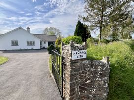 A driveway leading to a white house with a stone gatepost and iron gate with a sign reading orchard view at War Horse Valley Orchard View in Hatherleigh