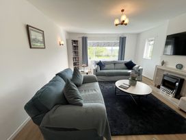 A living room with two sofas a coffee table a fireplace and a large window at War Horse Valley Orchard View in Hatherleigh