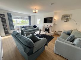 A living room with three sofas a round coffee table a fireplace and a wall mounted television at War Horse Valley Orchard View in Hatherleigh