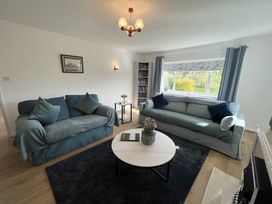 A living room with two sofas a round coffee table and a large window at War Horse Valley Orchard View in Hatherleigh