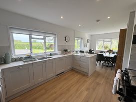 A kitchen with grey cabinets and a dining area with a table and chairs at War Horse Valley Orchard View in Hatherleigh