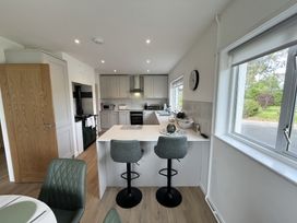A kitchen with gray cabinets a white island with two bar stools and a window showing greenery at War Horse Valley Orchard View in Hatherleigh