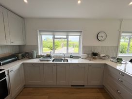 A kitchen with a sink under a window and cabinets at War Horse Valley Orchard View in Hatherleigh