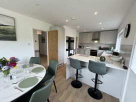 A kitchen with an island and bar stools next to a dining table set with placemats and flowers at War Horse Valley Orchard View in Hatherleigh