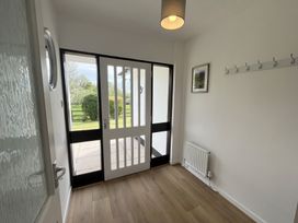 An entryway with a wooden floor a white door with glass panels a white radiator and a wall-mounted coat rack at War Horse Valley Orchard View in Hatherleigh