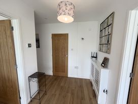 A hallway with wooden doors a small metal table a radiator cover with a wifi sign and a wall art at War Horse Valley Orchard View in Hatherleigh