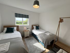 A bedroom with two single beds a nightstand between them and a wooden clothes rack at War Horse Valley Orchard View in Hatherleigh