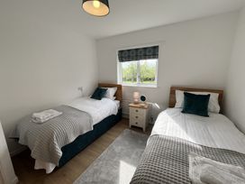 A bedroom with two single beds a nightstand between them and a window with a patterned blind at War Horse Valley Orchard View in Hatherleigh