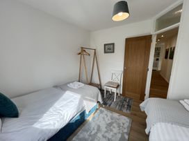 A bedroom with two single beds a chair a wooden clothes rack and a wooden door at War Horse Valley Orchard View in Hatherleigh