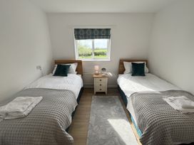 A bedroom with two single beds and a nightstand with lamp under a window at War Horse Valley Orchard View in Hatherleigh