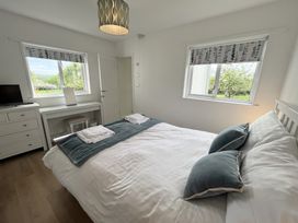 A bedroom with a bed a desk a chest of drawers and two windows at War Horse Valley Orchard View in Hatherleigh