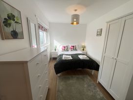 A bedroom with a double bed two bedside tables green lamps a white chest of drawers white wardrobe and a rug at War Horse Valley Orchard View in Hatherleigh