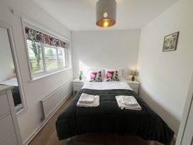 A bedroom with a bed with pillows and towels a window with floral curtains and bedside tables with lamps at War Horse Valley Orchard View in Hatherleigh