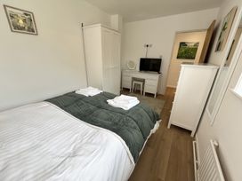 A bedroom with a bed folded towels on the bed a white wardrobe a white chest of drawers a white dressing table with a mirror and television at War Horse Valley Orchard View in Hatherleigh