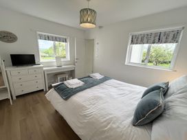 A bedroom with a bed pillows folded towels a dresser with a television and a desk with a stool at War Horse Valley Orchard View in Hatherleigh
