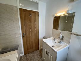 A bathroom with a wooden door a white sink cabinet with a mirror and light above it at War Horse Valley Orchard View in Hatherleigh