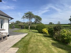 A garden with a lawn bushes trees and a bench near a building at War Horse Valley Orchard View in Hatherleigh