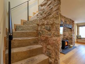 A staircase with stone wall and fireplace at Heathmoor in Horrabridge