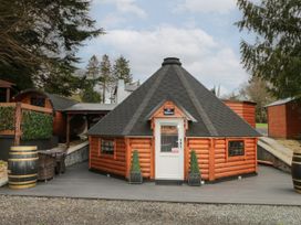 A wooden cabin with a black hexagon shingle roof a white door and two potted plants on a deck at The Hideaway in Dungiven Londonderry