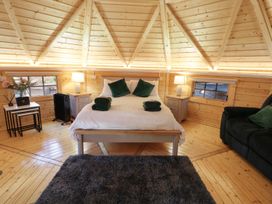 A bedroom with a bed a gray rug a black sofa and wooden walls at The Hideaway in Dungiven Londonderry