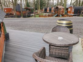 An outdoor seating area with a round wicker table and two chairs on a wooden deck at The Hideaway in Dungiven Londonderry