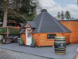 A small wooden cabin with a black shingled roof on a deck with a Guinness barrel and outdoor seating at The Hideaway in Dungiven Londonderry