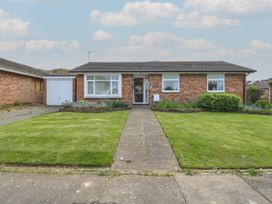 A brick bungalow with a tiled roof a front garden with a path and flower beds at White Lion Retreat in Cromer