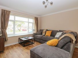 A living room with grey sofas and a coffee table in front of a large window at White Lion Retreat in Cromer