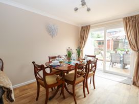 A dining area with wooden table and chairs set for six with wall decoration and sliding glass door to a garden at White Lion Retreat in Cromer