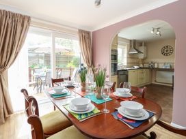 A dining room with a set table and a view into a kitchen through an archway at White Lion Retreat in Cromer