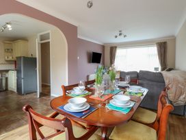 A dining table set with bowls and wine glasses in a room with an archway leading to a kitchen and a sofa near a window at White Lion Retreat in Cromer