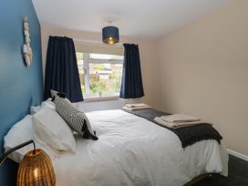 A bedroom with a bed with white bedding and black striped pillows a window with dark curtains and a bedside lamp at White Lion Retreat in Cromer