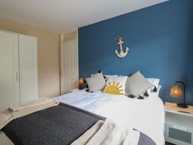 A bedroom with a bed pillows and blankets a white wardrobe and bedside tables with lamps at White Lion Retreat in Cromer