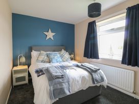A bedroom with a double bed blue accent wall star decoration bedside tables lamps and a window with blue curtains at White Lion Retreat in Cromer