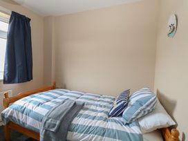 A bedroom with a wooden bed striped bedding and two pillows near a window with dark curtains at White Lion Retreat in Cromer