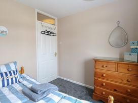A bedroom with a bed with striped bedding a wooden dresser with boxes and a teardrop-shaped mirror on the wall at White Lion Retreat in Cromer