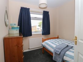 A small bedroom with a wooden bed and chest of drawers with boxes on top at White Lion Retreat in Cromer