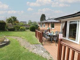 A patio with dining table umbrella and chairs in a garden at White Lion Retreat in Cromer