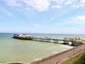 A pier extending into the sea with buildings on it and a walkway along the shore at White Lion Retreat in Cromer