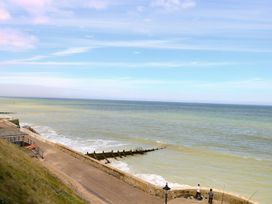 A coastal path beside the sea with waves and two people fishing at White Lion Retreat in Cromer
