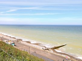 A coastal view with a pebbled beach a promenade and a wooden groyne extending into the sea at White Lion Retreat in Cromer
