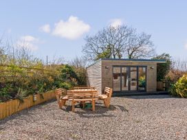 A garden with a wooden seating area and a shed at Capton Snug near Dartmouth